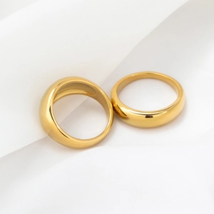 Detail of two minimalist polished 18k gold plated stainless steel rings on white fabric