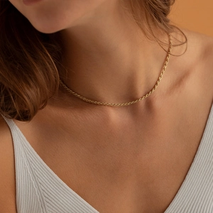 Detailopname van een 18K vergulde roestvrijstalen gedraaide touwketting gedragen door een model
