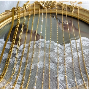 Collection of 18K gold plated stainless steel chains displayed on a vintage mirror