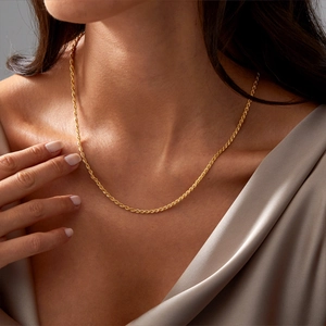 Detailopname van een 18K vergulde roestvrijstalen koordketting gedragen door een model
