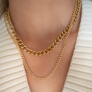 Close-up of layered 18K gold plated curb chain and thin figaro necklace on a model