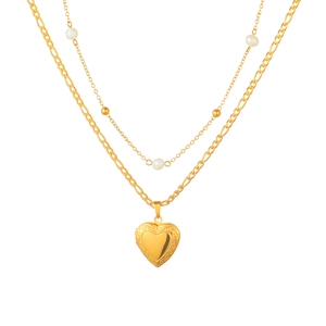 Dettaglio di una collana a doppio strato con medaglione a cuore d'oro e perle