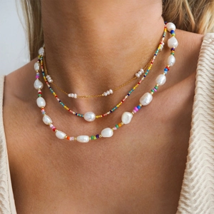Gros plan du collier à trois rangs avec perles baroques et perles colorées sur un modèle