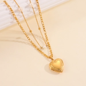 Dettaglio collana medaglione a cuore oro 18k con perle e catena figaro multistrato