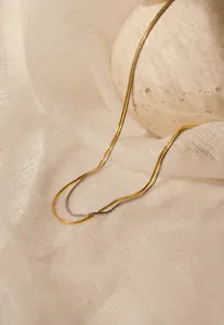 Detail of layered gold and silver snake chains on textured fabric background