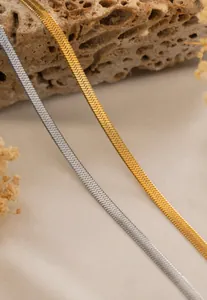 Detailed shot of 18K gold and silver flat snake chains on a natural stone background