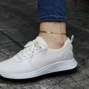 Flat gold snake chain anklet worn on ankle with white sneakers and blue jeans style