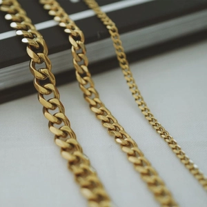 Detailed macro view of three 18K gold plated Figaro and Cuban link anklet chains