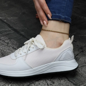 Close-up of gold 18K rope chain anklet worn on foot with casual white sneakers