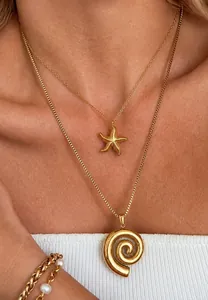 Close-up of layered 18k gold starfish pendant and spiral charm necklace set on model