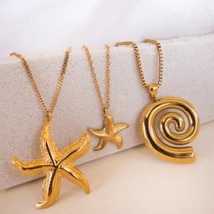 Gold 18k starfish and spiral pendant necklaces on minimalist white stone display