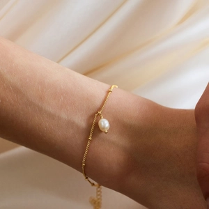 Detail of 18K gold plated stainless steel bracelet with white freshwater pearl on wrist