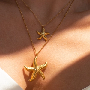 Golden starfish necklace set with 18k gold plated pendants worn on a model in sunlight