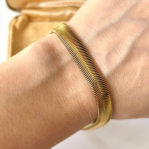 Detailoverzicht van de flexibele goudvergulde roestvrijstalen slangenarmband om de pols