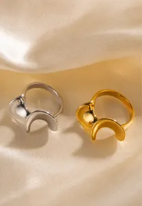 Detail of wavy S-shaped 18k gold and silver stainless steel rings on satin