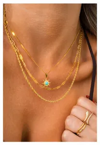 Detalle de collares dorados en capas con colgante de sol y anillo de serpiente con cristales