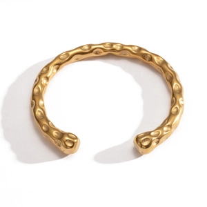 Détail d'un bracelet jonc en acier inoxydable plaqué or 18k avec une texture martelée