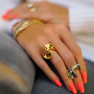 Detailed close-up of S-shaped wave rings in 18k gold and silver on model hands