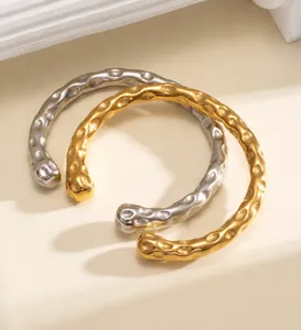 Gros plan de la texture martelée sur les bracelets joncs ouverts en acier doré et argent