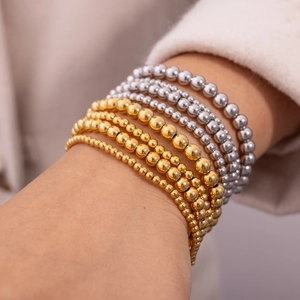 Mehrlagiges Stretch-Perlenarmband-Set in Gold und Silber auf weiblichem Handgelenk