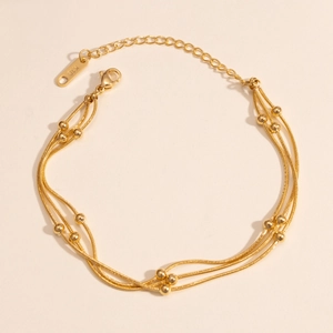 Detail eines 18K vergoldeten dreilagigen Edelstahl-Perlenarmbands mit Schlangenkette