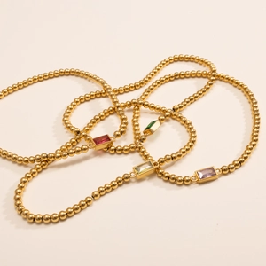 Detailopname van gouden kralenarmband met vier rechthoekige gekleurde geboortestenen