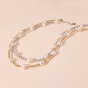 Dettaglio della collana di perle barocche a strati con perline d'oro e d'argento su sfondo