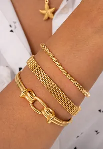 Dettaglio di bracciali a strati placcati oro inclusi catena a fune, maglia e rigido