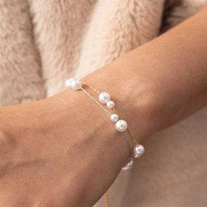 Elegantes zweischichtiges Perlenarmband mit Gold- und Silberketten am Damenhandgelenk