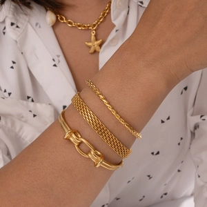 Dettaglio di tre bracciali in acciaio inossidabile placcati oro indossati a strati