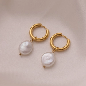 Detail of 18K gold-plated earrings with baroque pearls on soft pink silk fabric