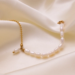 Detailed shot of 18K gold-plated bracelet with white baroque pearls on silk fabric