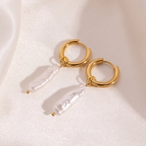 Detailed macro shot of 18K gold plated hoop earrings with baroque pearls on white satin
