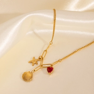 Close-up of gold star, shell, and red heart charms on an elegant link chain necklace