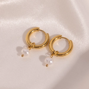 Detail of 18K gold plated hoop earrings with elegant hanging white pearl drops on white silk