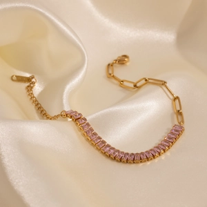 Detail of gold bracelet with pink rectangular crystals on champagne silk background