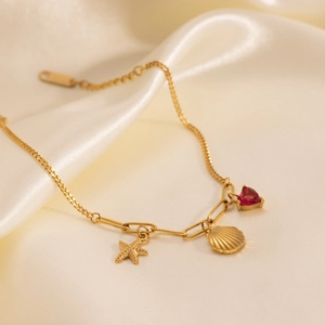 Detailed view of 18k gold plated bracelet with starfish, seashell and red heart charms