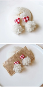 Detail of handmade heart stud earrings with plaid pattern and white fuzzy pompom charms