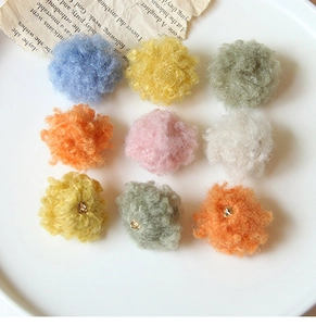 Dettaglio di pompon colorati in peluche per gioielli fai-da-te in un piatto di ceramica