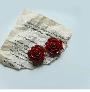 Artistic close-up of 24mm red resin rose flower charms for DIY jewelry and accessories