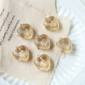 Elegant gold heart charms with vertical ridges on white textured background
