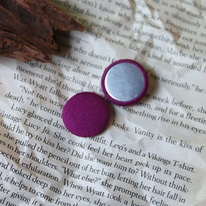 Close-up of purple fabric-covered round buttons with silver metal back on vintage book