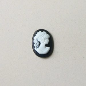 Détail d'un accessoire camée ovale vintage avec relief féminin blanc sur fond noir