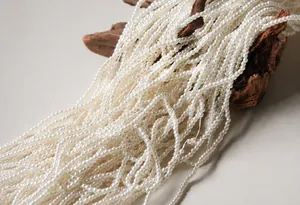 Detalle de perlas blancas de 3mm sobre madera, mostrando un acabado liso y brillante