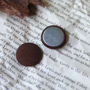 Detailed view of handmade dark brown fabric-covered round buttons with metal flat back