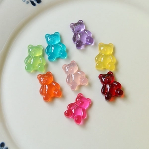 Macro shot of 8 translucent gummy bear resin charms in various colors on a ceramic plate