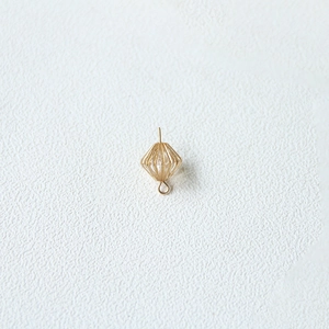 Macro shot of gold hollow rhombus lantern earring with pearl bead on white background