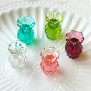 Close-up of five colorful miniature glass vases with ribbed texture on a white plate