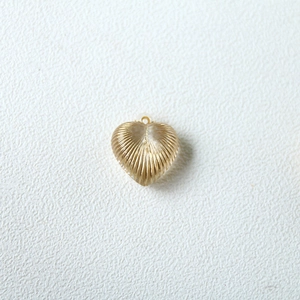 Detailed view of heart-shaped gold earring with textured radial patterns and clear center
