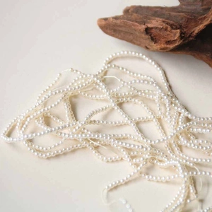 Primer plano de perlas blancas redondas de 3mm para creación de joyas DIY